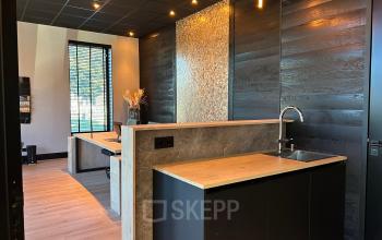 Modern workspace interior at Deltazijde 20b, Blaricum, featuring sleek wood paneling, a stylish counter with sink, and ambient lighting. Ideal office space rental with a contemporary vibe.