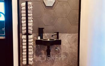 Office space at Deltazijde 20b, Blaricum showcasing a stylish wash area with hexagonal tiles and neatly stacked towels, perfect for refreshing breaks during office space rental.