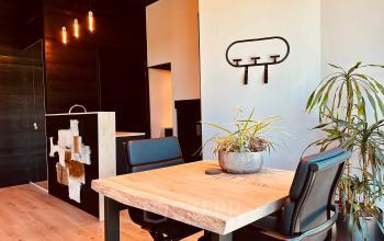 Modern office space with wooden table and black chairs at Deltazijde 20b, Blaricum, ideal for office space rental. Features contemporary lighting and stylish decor, offering a welcoming workspace.