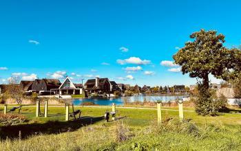 Scenic view of a business district in Blaricum, featuring modern architecture and a landscaped environment by a lake, highlighting the attractive location for office space rental opportunities.