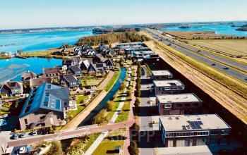 Exterior view of office buildings along a canal at Deltazijde 20b, Blaricum, with modern architecture and scenic surroundings, ideal for those seeking office space rental.