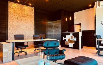 Stylish modern office at Deltazijde 20b, Blaricum featuring sleek wooden desks and leather chairs, ideal for office space rental. The space is well-lit with contemporary decor and minimalist design.