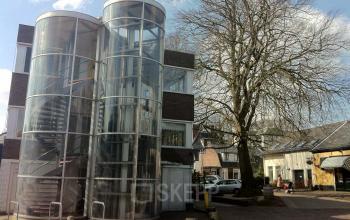 Exterior view of the office building at Zomerzorgerlaan 50, Bloemendaal. The building features unique cylindrical glass staircases.