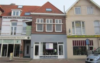 Exterior view of an office to rent at Zomerzorgerlaan 50, Bloemendaal, with a storefront below residential windows in a multi-story building.