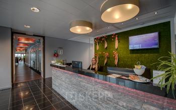 Reception area in modern office space with a smiling receptionist at Tolnasingel 1-3, Bodegraven, ideal for rent office space needs.