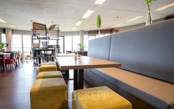 Spacious and bright furnished office space at Tolnasingel 1 - 3, Bodegraven, featuring modern seating and large windows.
