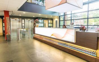 Bright office reception area at Ceresstraat 1, Breda Centrum-Station, featuring modern design with a front desk and seating area, perfect for office space rental.