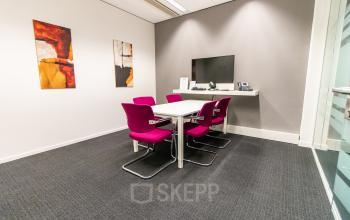 Furnished office space at Ceresstraat 1, Breda Centrum-Station with a meeting table, pink chairs, and wall art, available for office space rental.