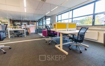Bright office space at Ceresstraat 1 with modern furnishings including desks and chairs. Individual working at a desk, ideal for those seeking office space rental in Breda Centrum-Station.