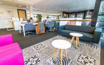 Interior office space for rent at Ceresstraat 1, Breda Centrum-Station featuring modern furnishings, desks, and seating areas. A person is working at a desk.