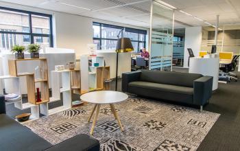 Modern furnished office space in Breda Centrum-Station with sofas, shelving, and desks, perfect for office space rental activities.