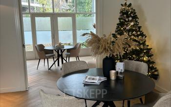 Cozy and inviting office space with a decorated Christmas tree, ideal for rent in Breda Centrum-Station, featuring a round table and chairs, perfect for meetings.