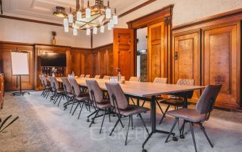 Spacious conference room at Ceresstraat 13, Breda Centrum-Station, featuring a long table with chairs, wood-paneled walls, and a TV. Ideal office space rental for meetings or presentations.