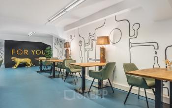 Stylish office space for rent at Ceresstraat 13, Breda Centrum-Station with modern furnishings and unique decor, featuring wooden tables and green chairs.
