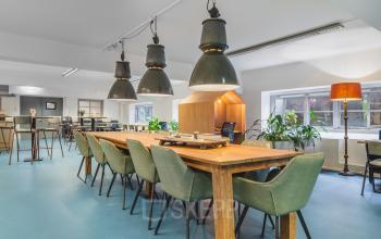 Spacious furnished workspace with wooden tables, stylish green chairs, and large ceiling lights, ideal for office space rental at Ceresstraat 13 in Breda Centrum-Station.