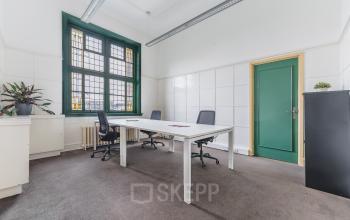 Bright office space with modern furnishings, featuring large windows and a simple, clean design, ideal for office space rental in Breda Centrum-Station.