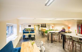 Modern office space rental at Ceresstraat 13 in Breda Centrum-Station with well-lit, open floorplan and occupants engaged in tasks at communal tables.