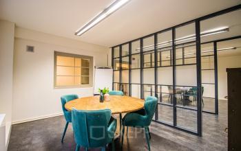 Contemporary office space rental at Ceresstraat 13 in Breda Centrum-Station with a round table and comfortable seating in a well-lit room with glass walls.
