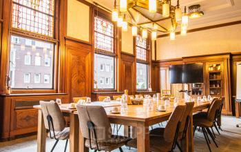 Chic office space rental at Ceresstraat 13, in Breda Centrum-Station with elegant wood paneling and a large conference table set for a meeting.