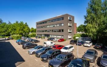 Exterior view of Westboek 36-66 in Breda Noord-West, featuring a modern office building with ample parking space in the foreground. Ideal location for office space rental.