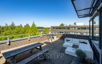 Roof terrace of the office to rent at Westboek 36-66, Breda Noord-West. Features a wooden picnic table, outdoor seating, and views of surrounding buildings.