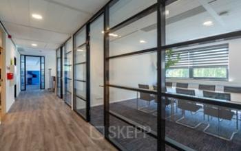 Modern office space with glass partitions and wooden flooring at Westboek 36-66, Breda Noord-West. Bright meeting room visible through transparent walls, ideal for office space rental.
