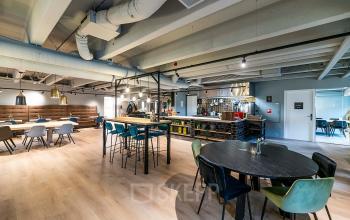 Spacious and modern office interior at Heerbaan 14, Breda Oost-Brabantpark, featuring open seating areas and high tables, ideal for collaborative work and meetings. Perfect choice for office space rental.