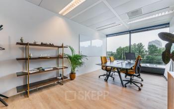 Modern office to rent at Heerbaan 14, Breda Oost-Brabantpark, featuring bright workspaces with large windows, wooden flooring, and minimalistic furnishings including a desk, chairs, and shelves, offering a professional atmosphere.