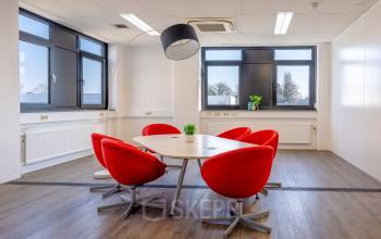 Bright office space with red chairs around a modern table at Druivenstraat 25-31, ideal for businesses looking for office space rental in Breda Oost.