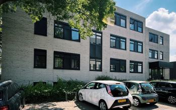 Exterior view of an office building at Druivenstraat 25-31 in Breda Oost, with cars parked in front, ideal for office space rental.