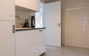 Compact kitchenette in an office at Druivenstraat 25-31, Breda Oost, featuring white cabinets and a tiled floor, perfect for office space rental.