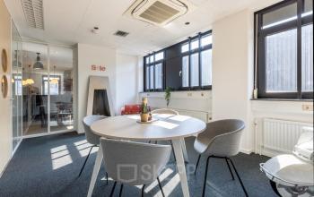 Bright office space for rent at Druivenstraat 25-31 in Breda Oost, featuring a round table with chairs and modern lighting.