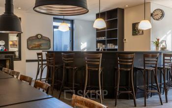 Spacious office lounge area with high stools at a sleek bar counter, ideal for casual meetings or breaks. Perfect spot for office space rental at Druivenstraat 25-31, Breda Oost.