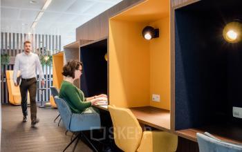 Modern office space rental at Leonardo Da Vincilaan 1, Brussels Airport, featuring individual workstations with bright yellow accents and contemporary lighting.