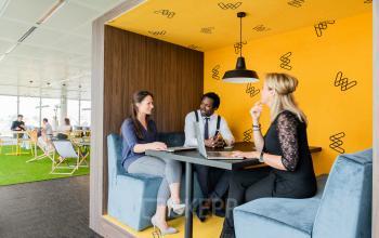 Modern furnished office space for rent at Leonardo Da Vincilaan 1 in Brussels Airport, featuring collaborative workspaces with employees in discussion.