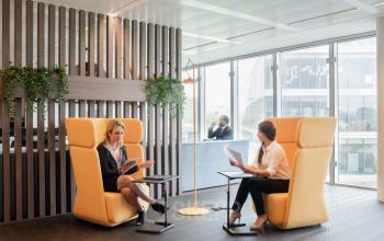 Modern office lounge at Leonardo Da Vincilaan 1 in Brussels Airport with comfortable seating and natural light, featuring people engaged in business discussions.
