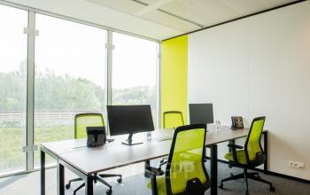 Furnished office space with desks and chairs by large windows at Leonardo Da Vincilaan 1, Brussels Airport.