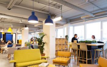 Modern office space at Pegasuslaan 5, Brussels Airport, featuring a stylish interior with seating areas and individuals engaged in conversation and work. Ideal for office space rental.