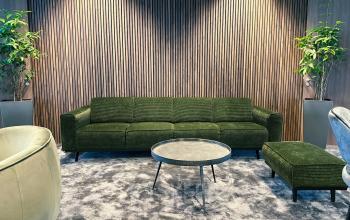 Cozy lounge area with green sofa, armchairs, small table, and potted plants at office space rental, Leonardo Da Vincilaan 19, Brussels Airport.