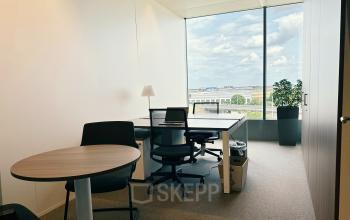 Bright office space at Leonardo Da Vincilaan 19 in Brussels Airport with large window, modern furniture, and greenery.