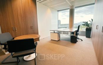 Office space rental at Leonardo Da Vincilaan 19, Brussels Airport, featuring a clean workspace with a desk, chairs, and a large window with natural light.