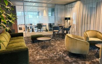 Modern office lounge at Leonardo Da Vincilaan 19, Brussels Airport with stylish seating and glass partitioned workspaces in the background.