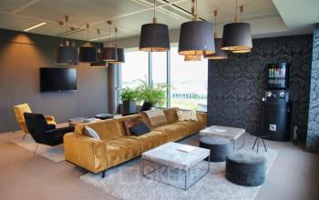 Elegant lounge area in office space rental at Leonardo Da Vincilaan 19, Brussels Airport, Brussels, with modern sofas, a TV, and large windows.