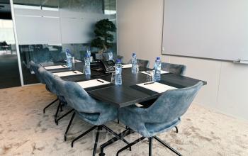 Modern conference room with a large table, padded chairs, whiteboard, and conference phone at Leonardo Da Vincilaan 19, Brussels Airport.