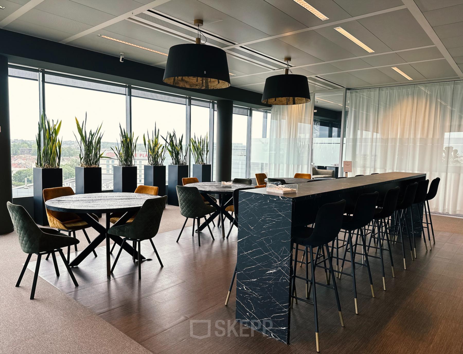Modern furnished office space with large windows, plants, tables, and high seating at Leonardo Da Vincilaan 19, Brussels Airport, available for office space rental.