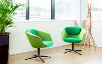Kantoor te huur op Davincilaan 1, Brussel Airport met een moderne inrichting, grote ramen en groene stoelen bij een raam.