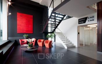 Multifunctionele kantoorruimte te huur op Davincilaan 1, Brussel Airport met moderne wachtruimte, trappen en kleurrijke stoelen.