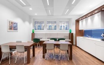 Modern furnished office space with wooden tables, chairs, and a kitchen area located at Koloniënstraat / Rue des Colonies 11 in Brussels Center.
