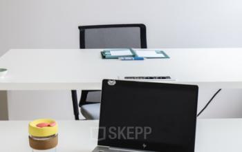 Kantoorruimte te huur op Rue du Congres 37 in Brussel met strakke werkplekken inclusief bureaus en stoelen, met zichtbare laptop en koffiekop.