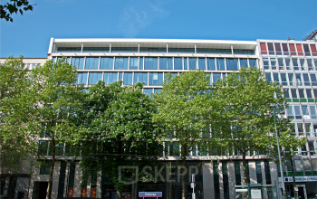Exterior view of the office building located at Louizalaan / Avenue Louise 143 in Brussels Elsene, with trees in the foreground and cars parked in front.